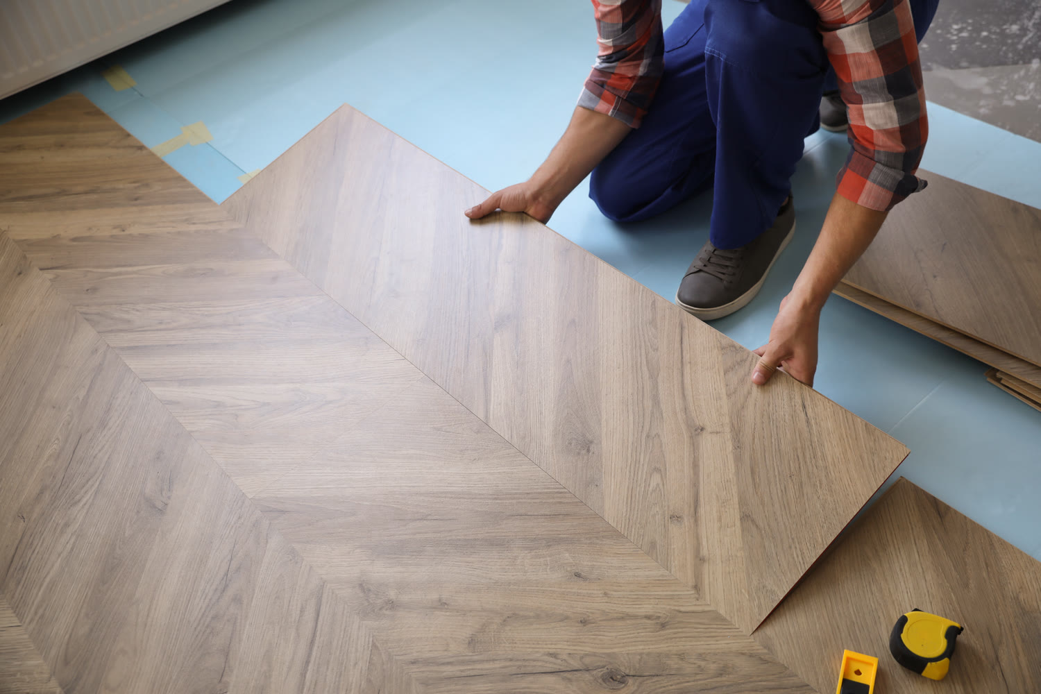 Installer positioning a large chevron-pattern LVT board on a prepared subfloor