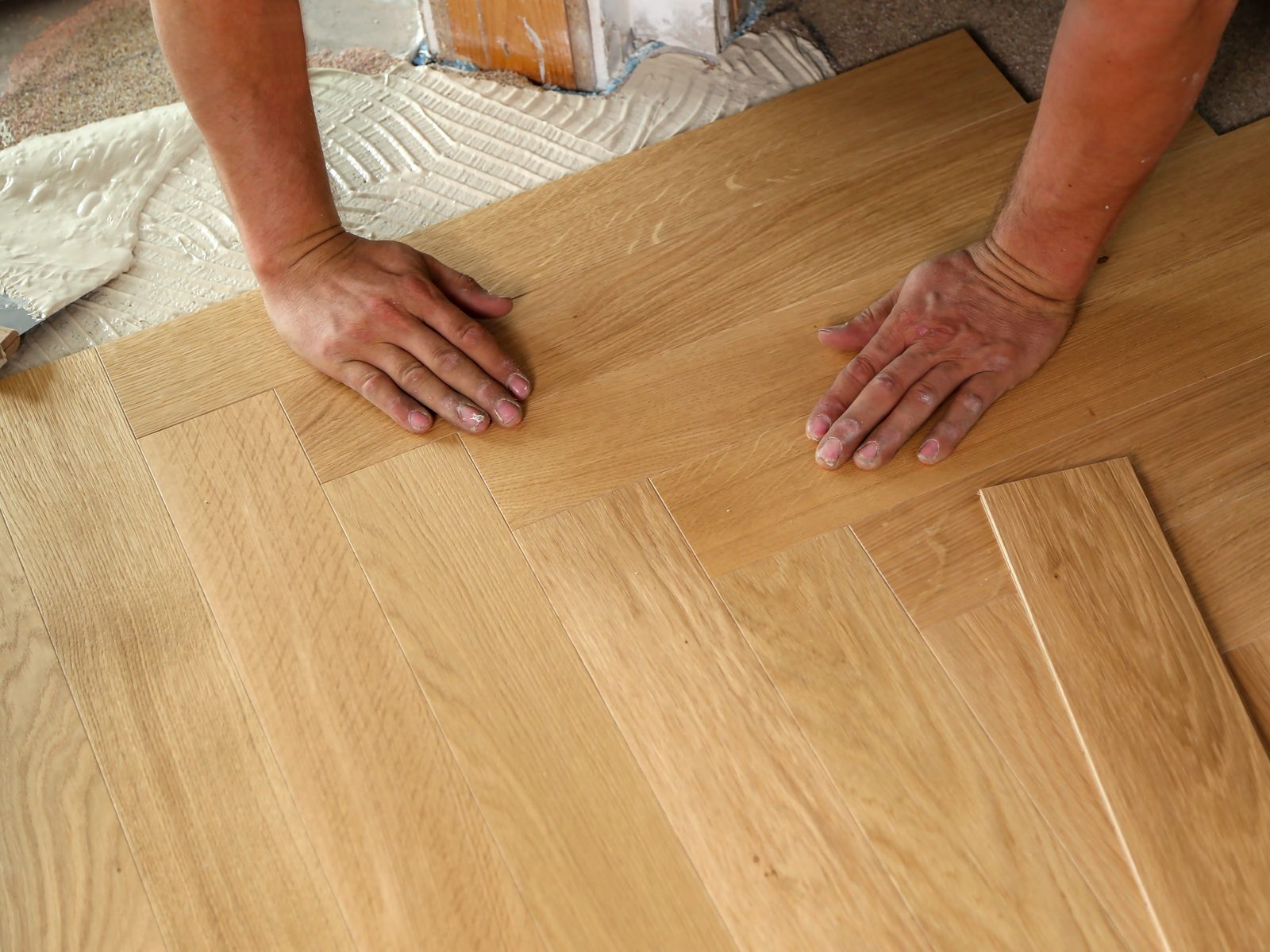 Craftsman carefully handling a finished Versailles parquet panel on a workbench