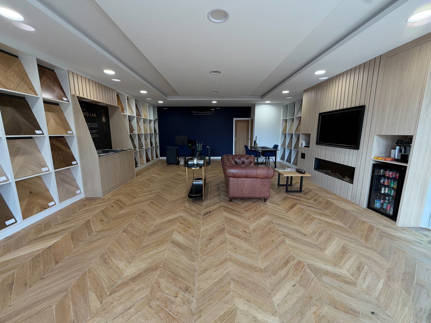 Inside the Hampton Hill Flooring showroom — chevron oak flooring, display bays and a Chesterfield sofa