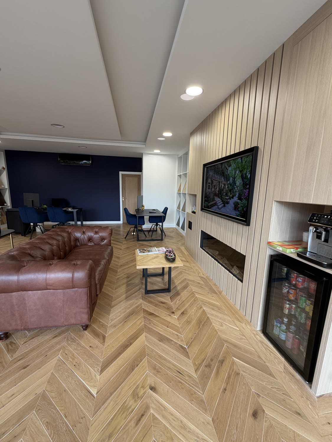The Lighting Lab area of the Hampton Hill Flooring showroom — chevron oak floor beneath a slatted wood feature wall, seating area with a framed artwork